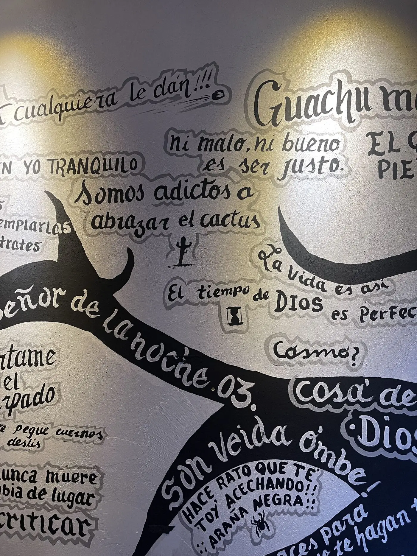 La pared clara del bar, escrita de arriba abajo con dichos pintados a mano