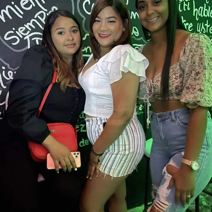 Tres amigas arregladas frente a la pared de los dichos