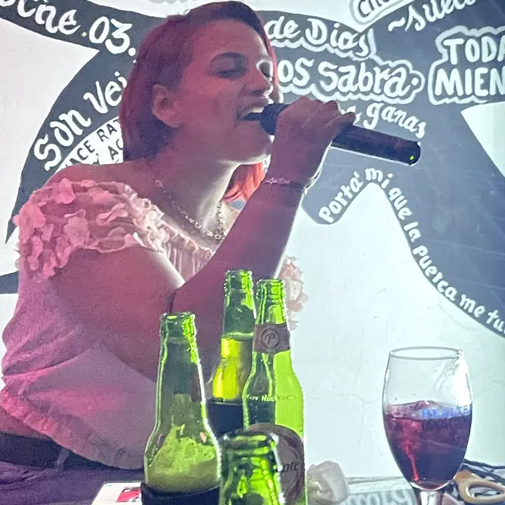 Una clienta cantando karaoke con el micrófono en la mano